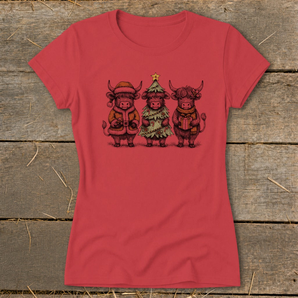 Three highland cows wearing Christmas attire: one as Santa, one as a tree, one holding a gift.