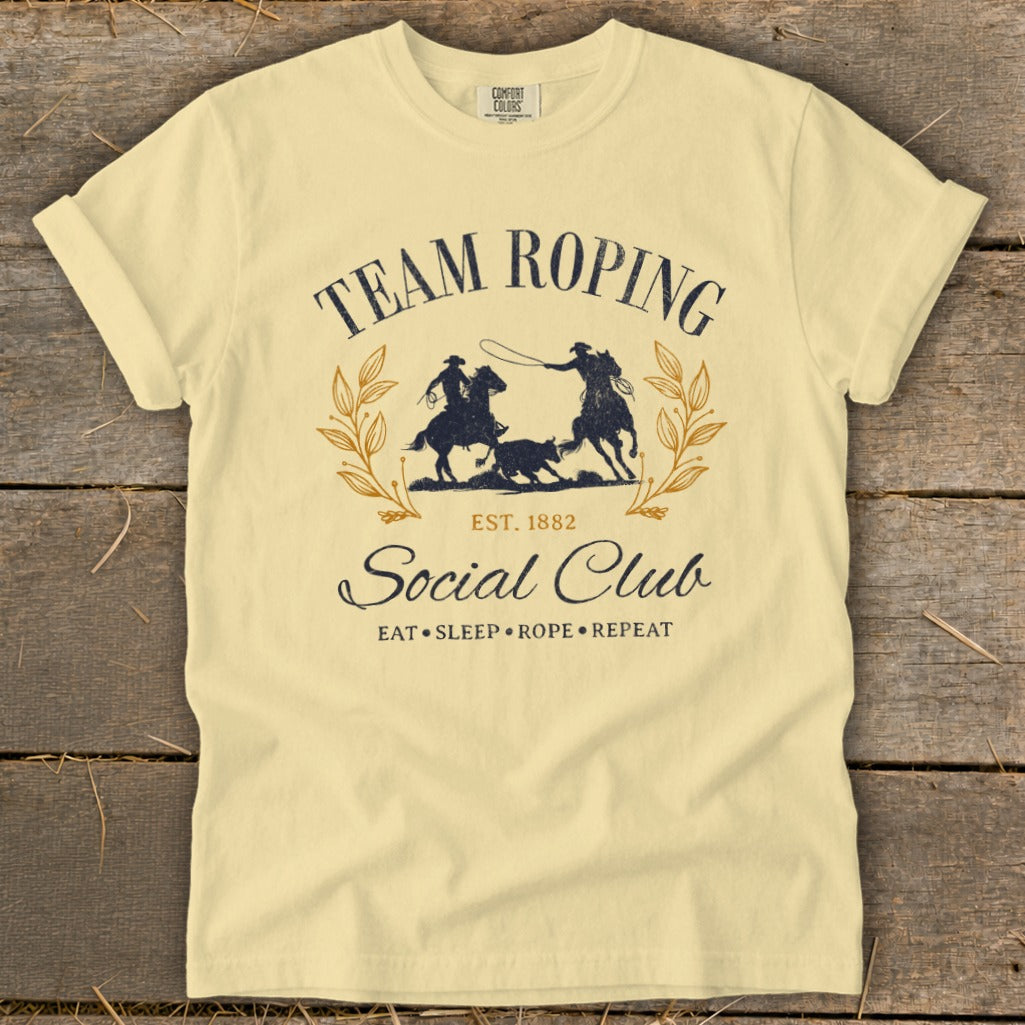Light yellow t-shirt with "Team Roping Social Club" graphic and cowboys roping a calf.