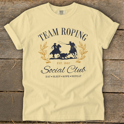 Light yellow t-shirt with "Team Roping Social Club" graphic and cowboys roping a calf.