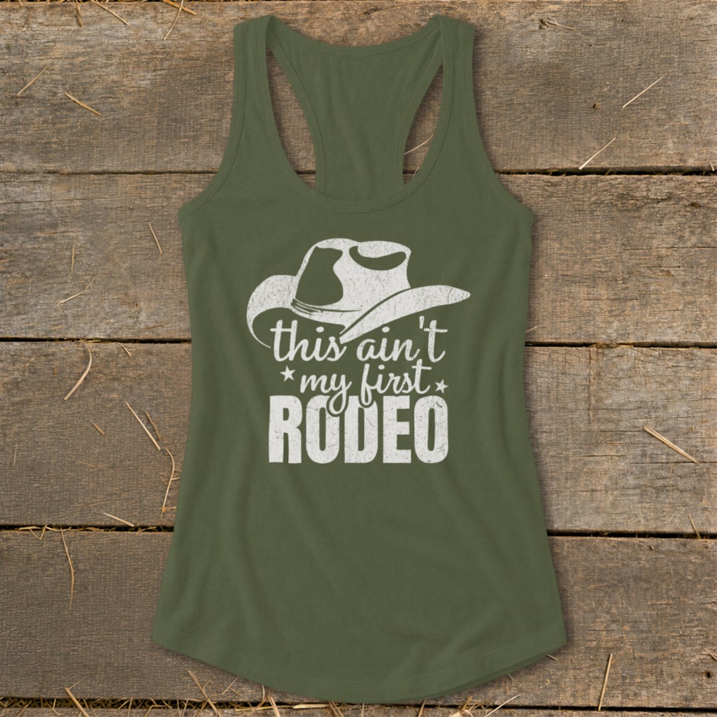 Green tank top with white "this ain't my first RODEO" text and cowboy hat graphic.