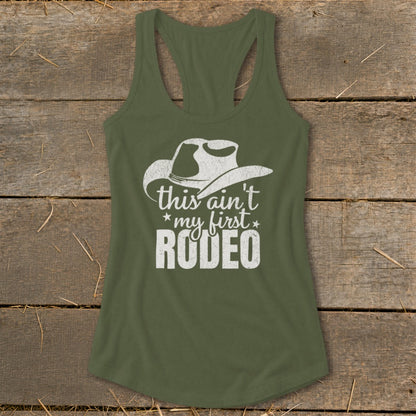 Green tank top with white "this ain't my first RODEO" text and cowboy hat graphic.