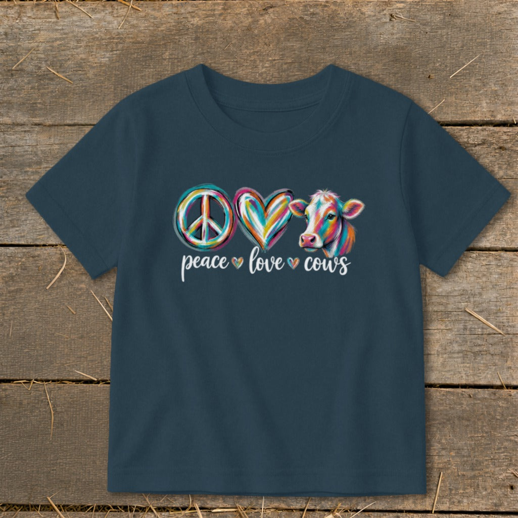 T-shirt with peace, love, cows design featuring a cow and colorful symbols.