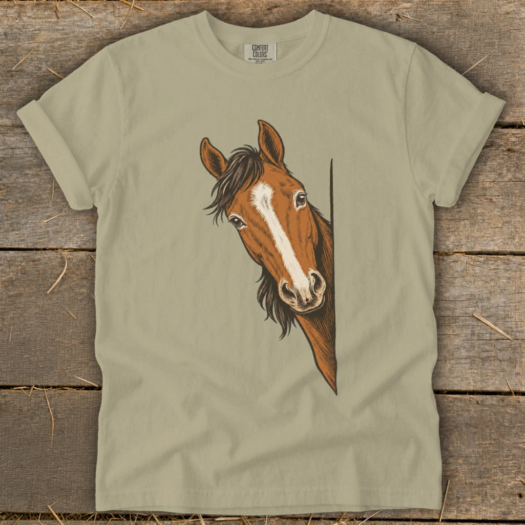Brown horse with white blaze peeking around a corner on a tan t-shirt.