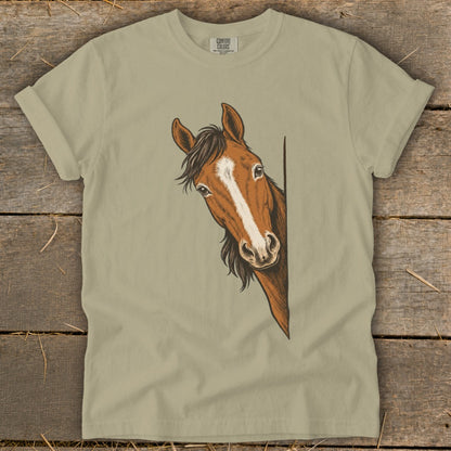 Brown horse with white blaze peeking around a corner on a tan t-shirt.