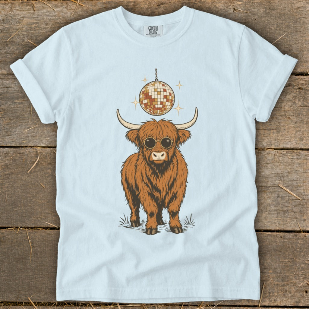 Highland cow wearing sunglasses under a disco ball on a light blue t-shirt.