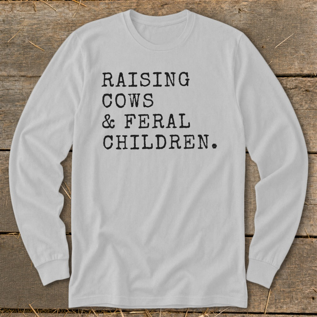 White long-sleeve t-shirt with black text: "RAISING COWS & FERAL CHILDREN."