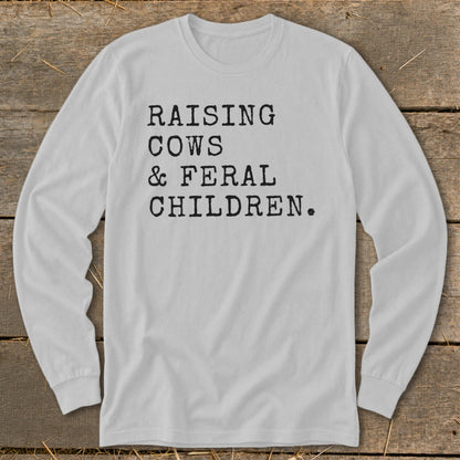 White long-sleeve t-shirt with black text: "RAISING COWS & FERAL CHILDREN."
