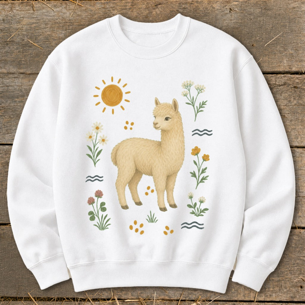White sweatshirt with a cream-colored alpaca illustration surrounded by flowers and sun.