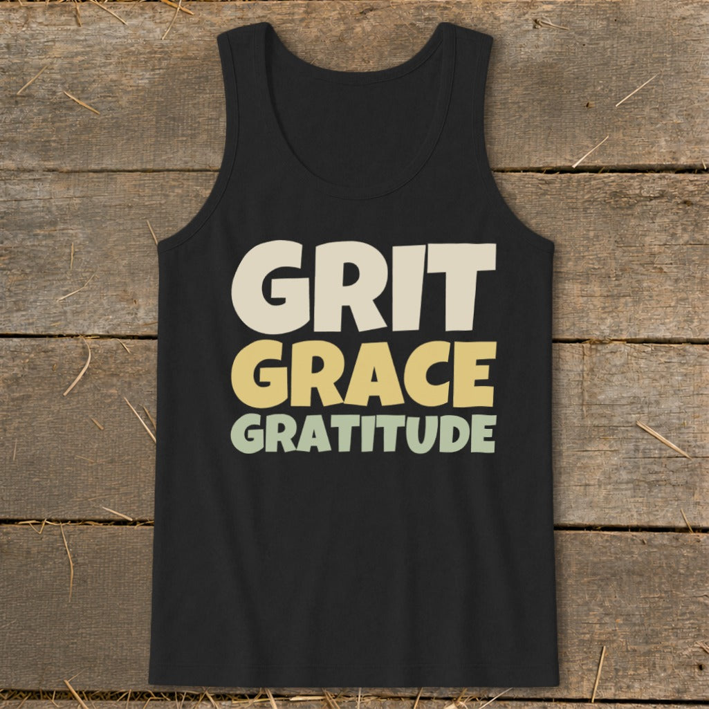 Black tank top featuring the text GRIT GRACE GRATITUDE in stacked, colorful block letters against a wooden background.