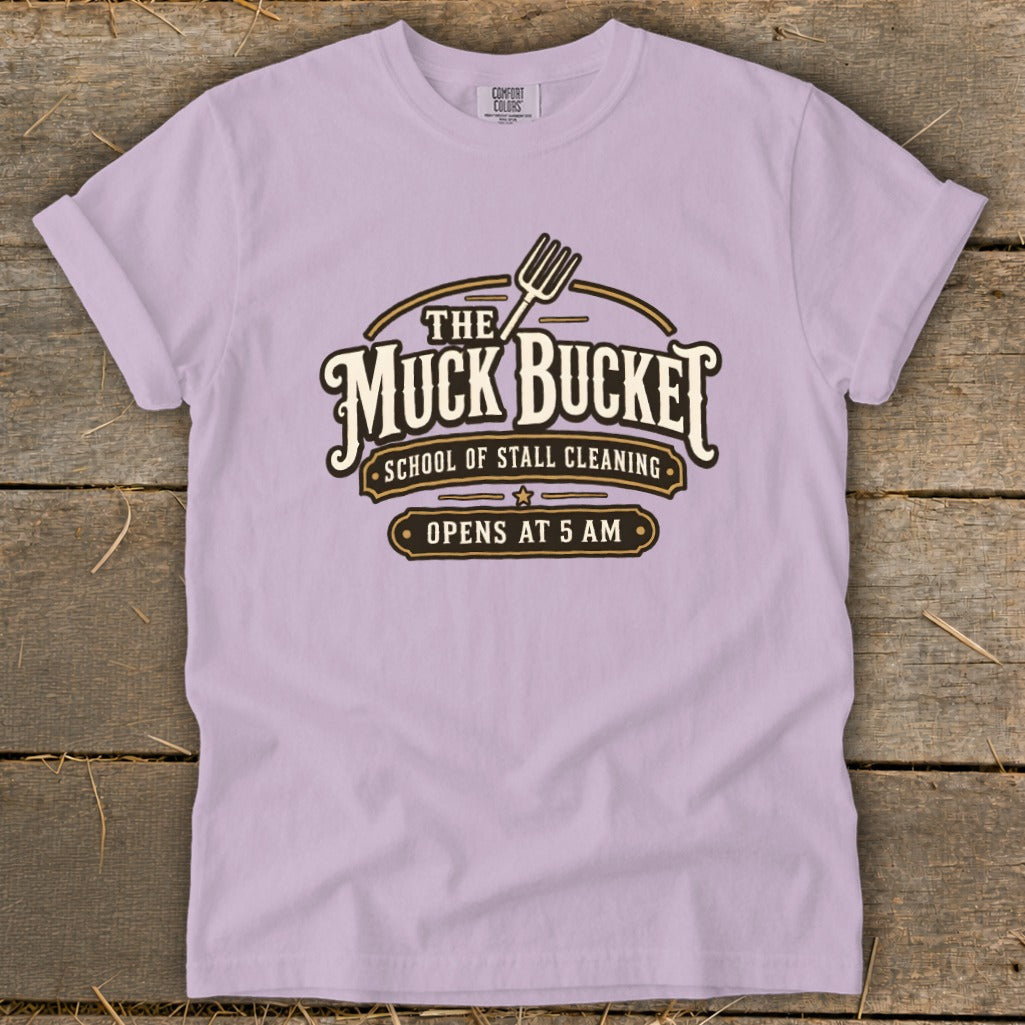 Light purple t-shirt with "The Muck Bucket School of Stall Cleaning Opens at 5 AM" graphic.