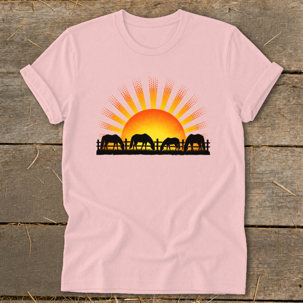 Silhouette of horses grazing in front of a rising sun with rays.