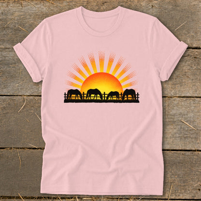 Silhouette of horses grazing in front of a rising sun with rays.