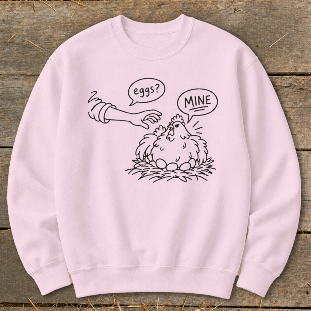 Pink sweatshirt with black line art of a chicken protecting eggs, saying "MINE".
