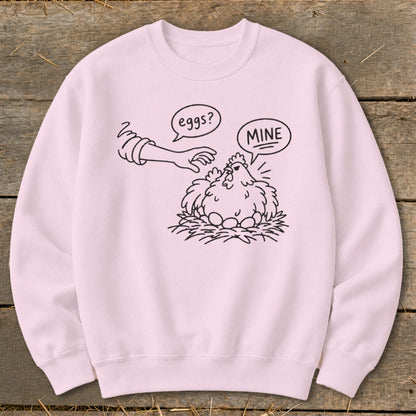 Pink sweatshirt with black line art of a chicken protecting eggs, saying "MINE".