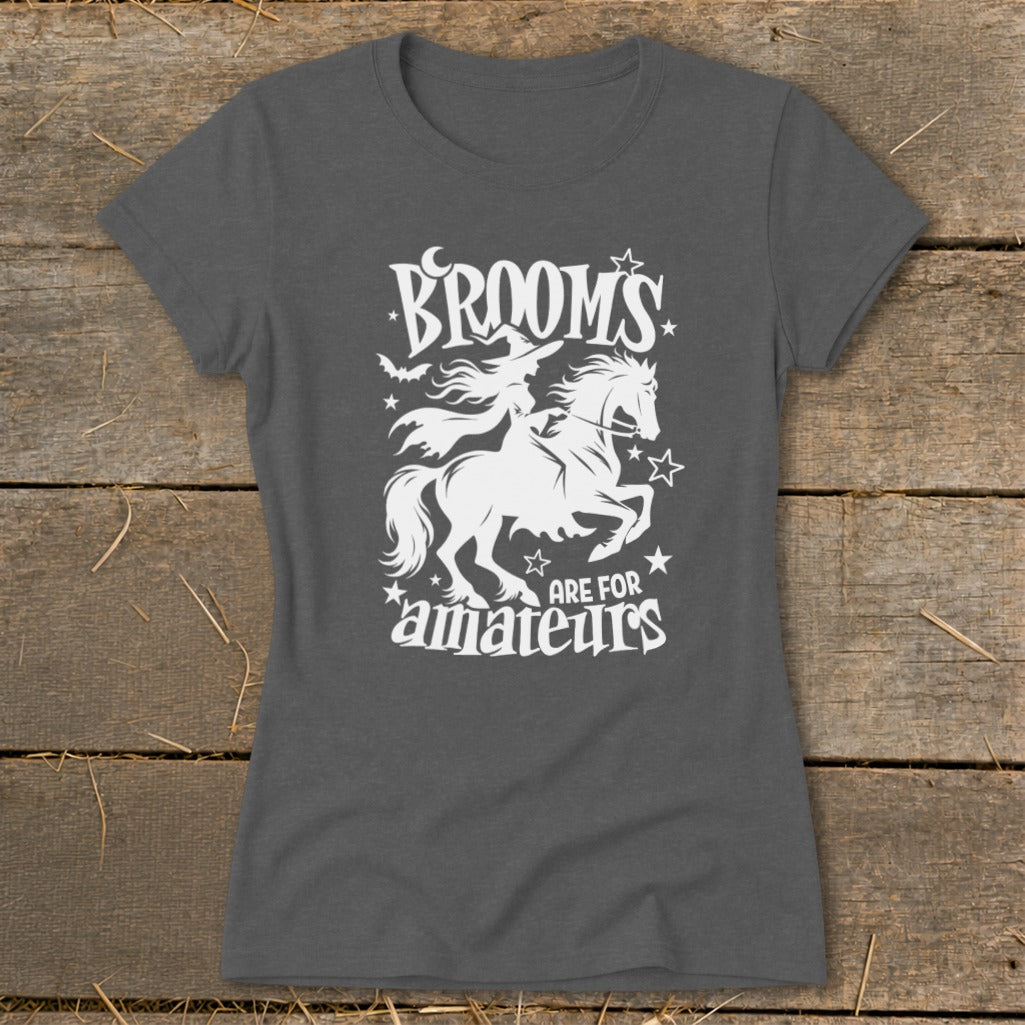 Dark grey t-shirt with white graphic: witch on horse, bats, moon, stars, and text "BROOMS ARE FOR amateurs".