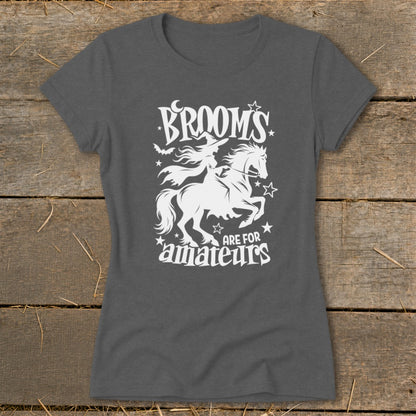 Dark grey t-shirt with white graphic: witch on horse, bats, moon, stars, and text "BROOMS ARE FOR amateurs".