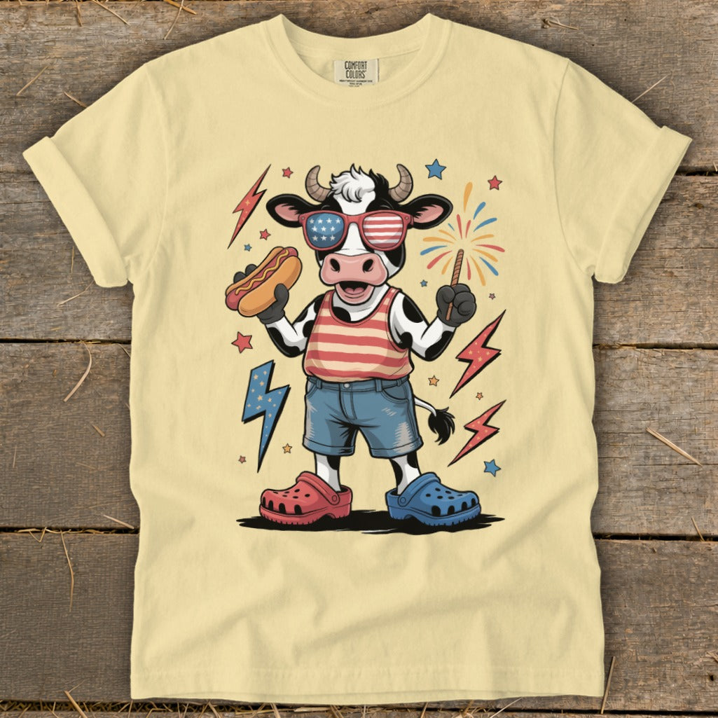 Cartoon cow wearing American flag sunglasses and holding a hot dog.
