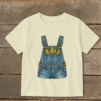 Cream t-shirt with a graphic of denim overalls filled with corn on the cob.