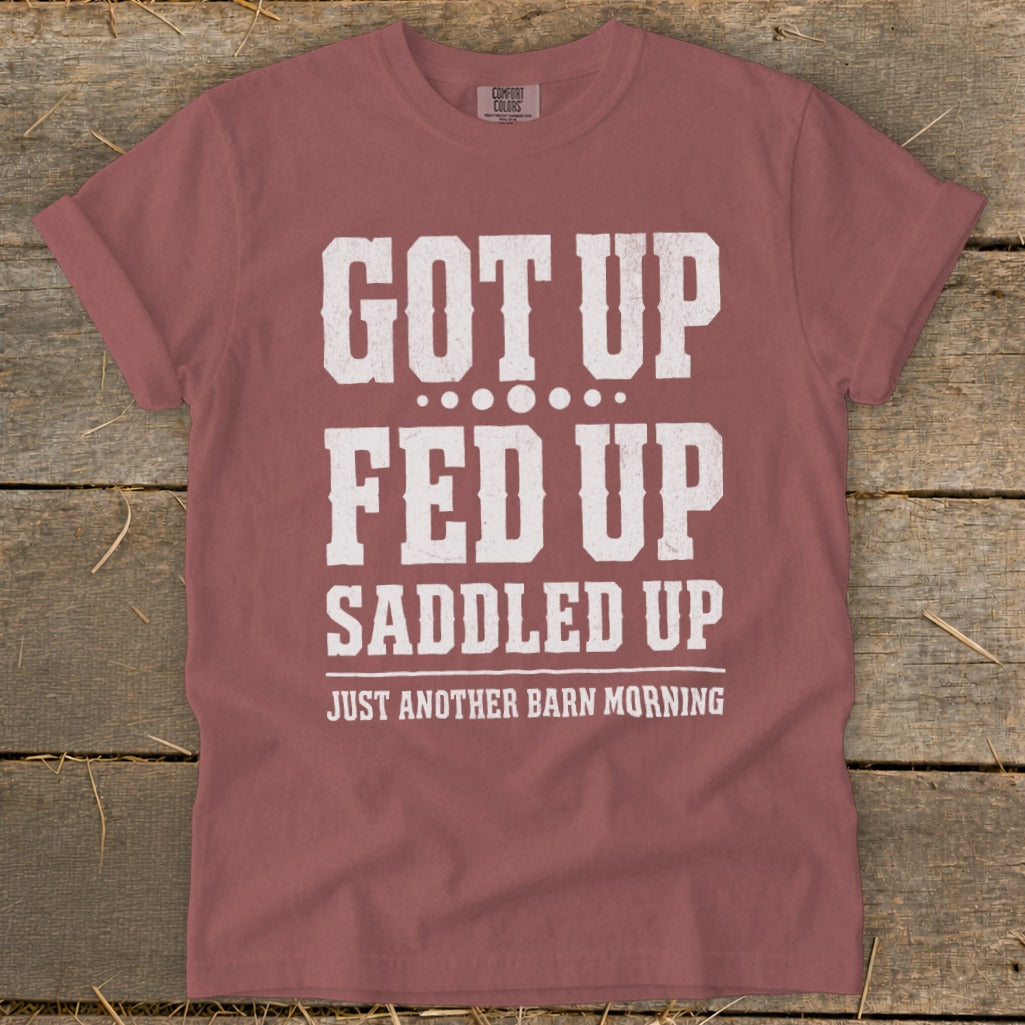 Red t-shirt with distressed text reading "GOT UP FED UP SADDLED UP JUST ANOTHER BARN MORNING".