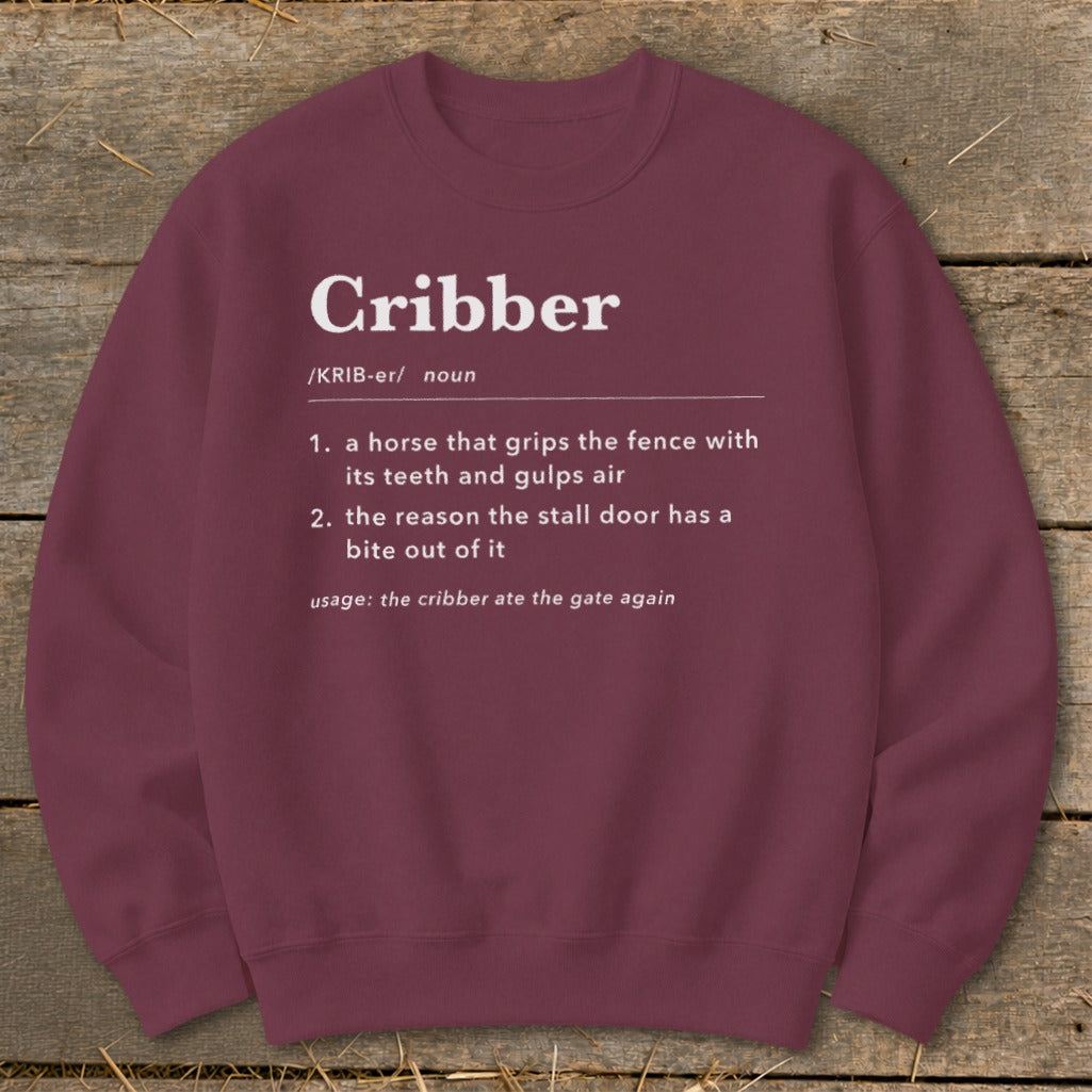 Maroon crewneck sweatshirt featuring a dictionary-style definition of the word cribber printed in white.