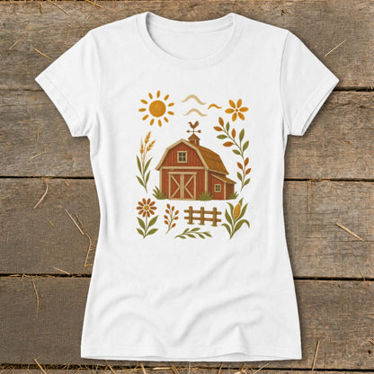 White t-shirt with a rustic farm scene featuring a red barn, sun, flowers, and fence.