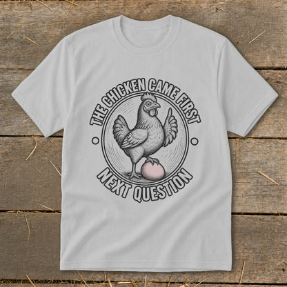 T-shirt graphic with chicken on egg, text "The chicken came first, next question".