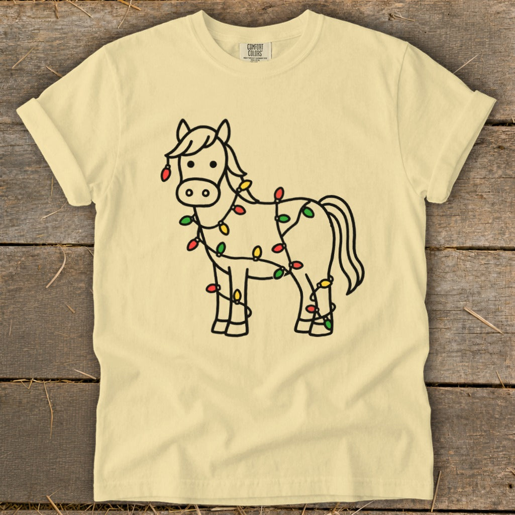Light yellow t-shirt with a black outline drawing of a horse wrapped in colorful Christmas lights.