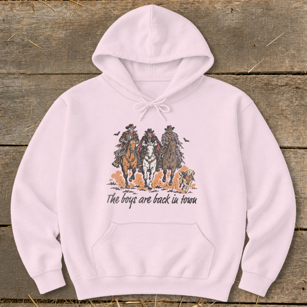 Pink hoodie with graphic of three skeleton cowboys on horses and a dog, text "The boys are back in town."