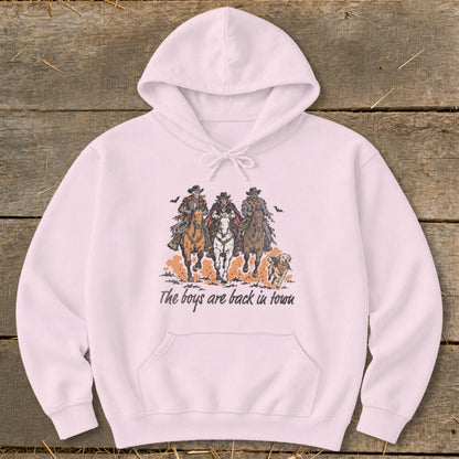 Pink hoodie with graphic of three skeleton cowboys on horses and a dog, text "The boys are back in town."