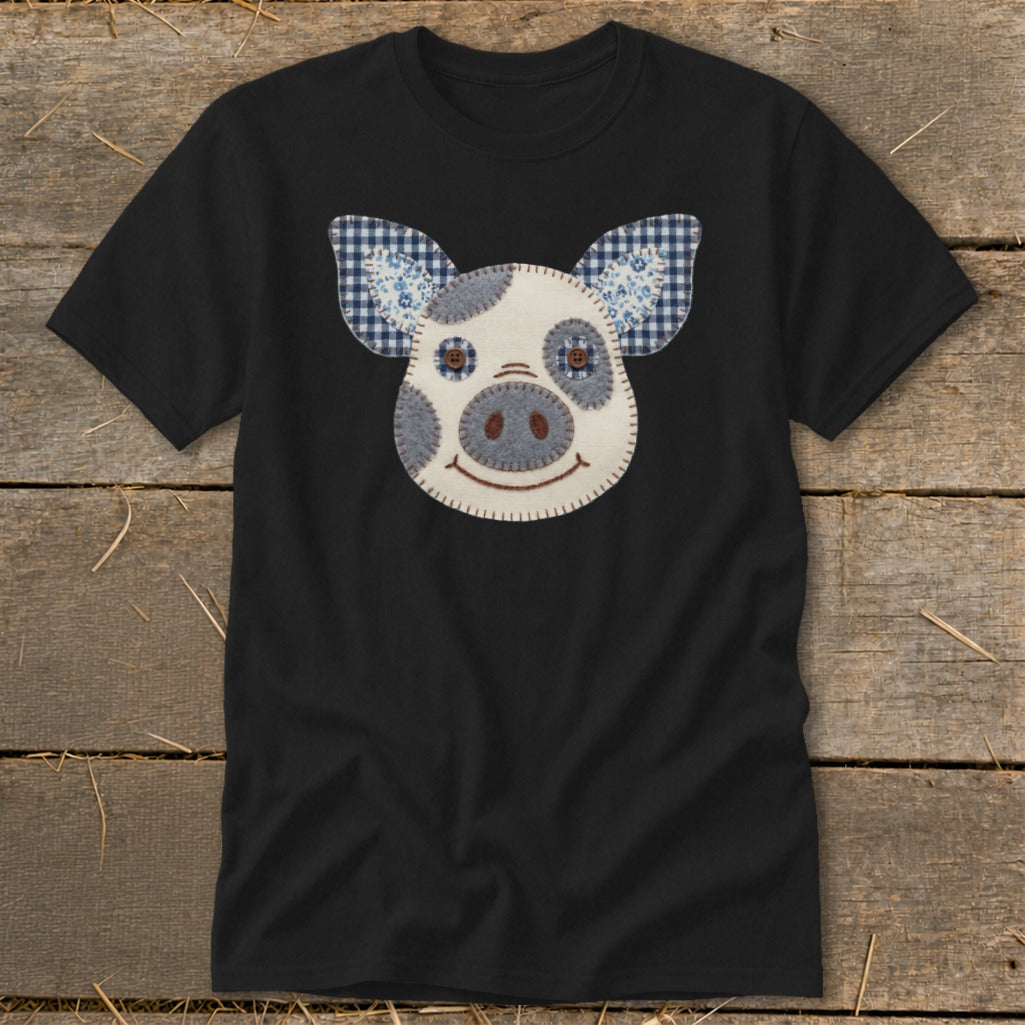 Black t-shirt with a pieced fabric pig face applique and plaid ears.