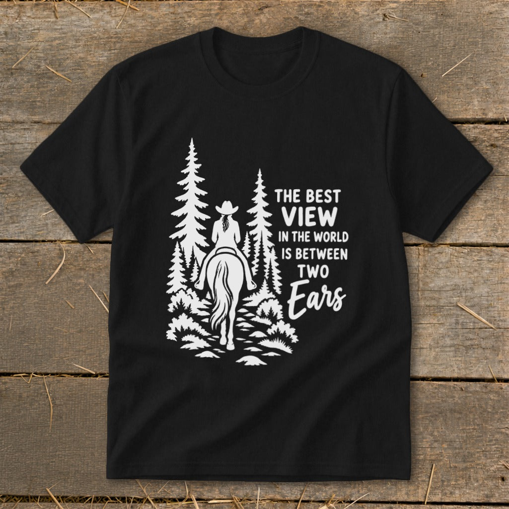 Black t-shirt featuring a white graphic of a horseback rider in the forest with text reading The Best View in the World is Between Two Ears.