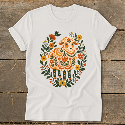 White t-shirt with a colorful folk art sheep surrounded by a floral wreath.