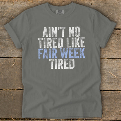 Gray t-shirt with distressed text "AIN'T NO TIRED LIKE FAIR WEEK TIRED".