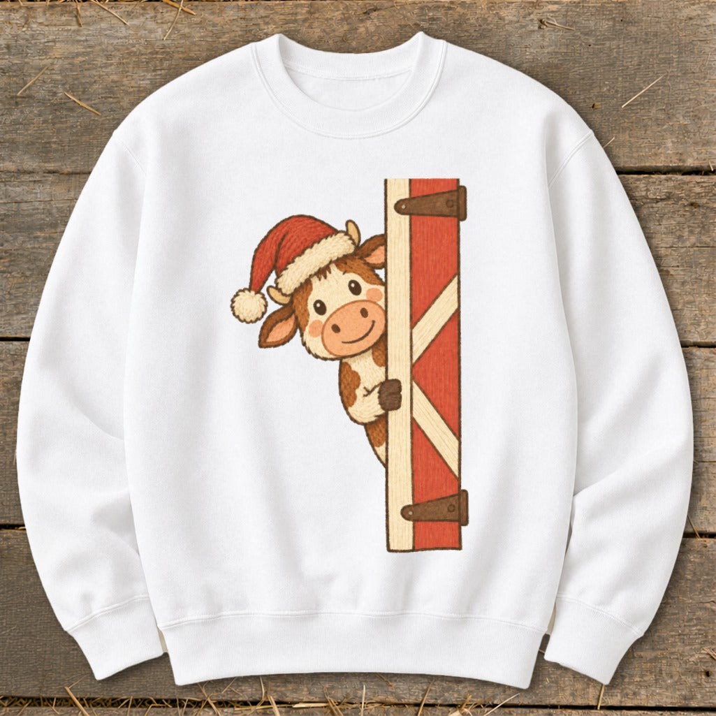 White sweatshirt with a cow wearing a Santa hat peeking from behind a barn door.
