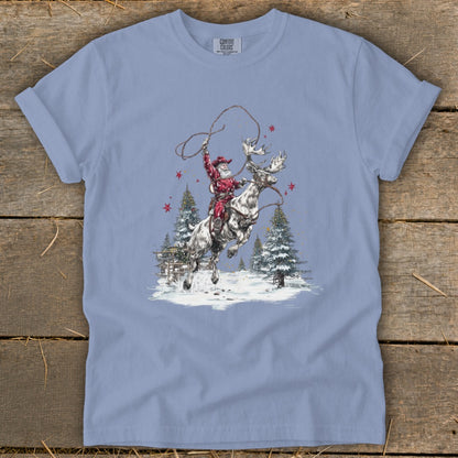 Santa rides a reindeer while holding a lasso in a snowy forest scene.