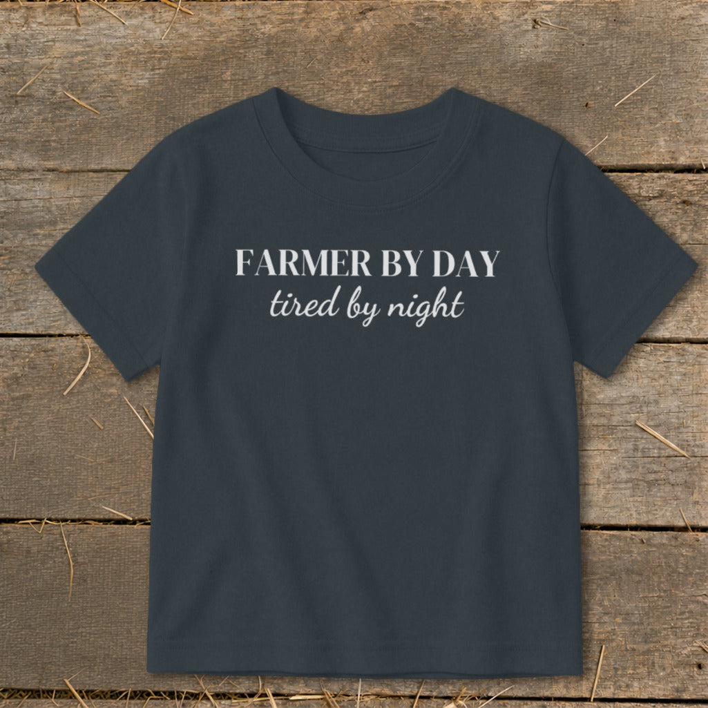 Dark gray t-shirt with white text "FARMER BY DAY tired by night".