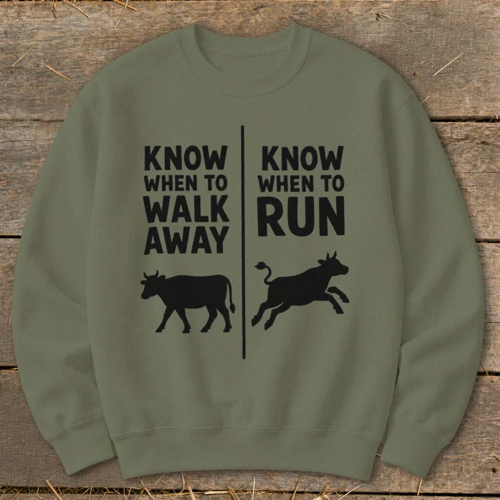 Olive green sweatshirt with black text: "KNOW WHEN TO WALK AWAY" and "KNOW WHEN TO RUN" with cow graphics.