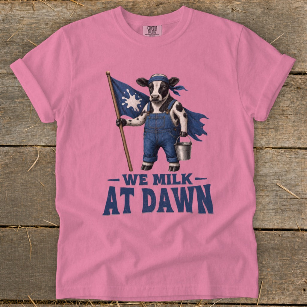 Pink t-shirt with a cow holding a flag and the text "We Milk At Dawn".