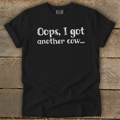 Black t-shirt with white text that reads "Oops, I got another cow..."