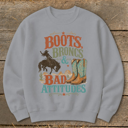 Crewneck sweatshirt with "Boots, Broncs & Bad Attitudes" text, cowboy, and boots graphic.