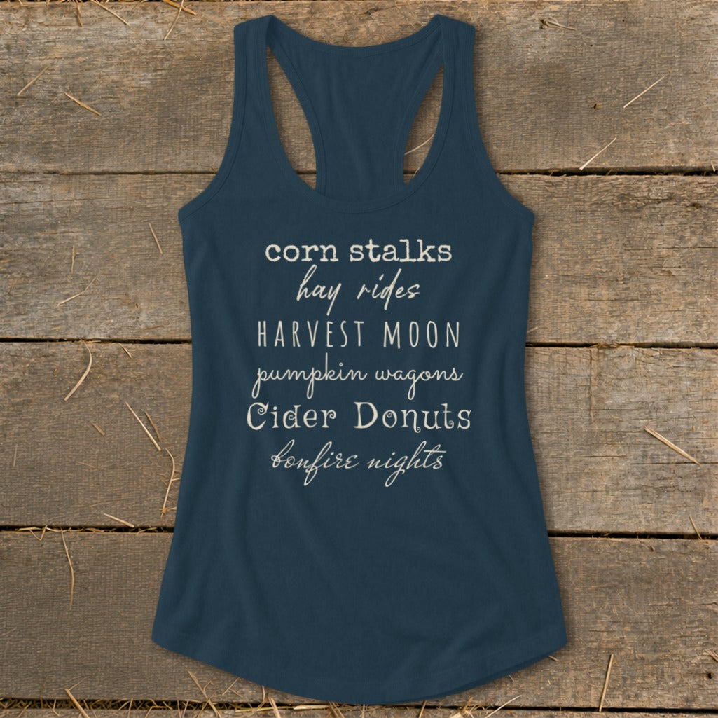 Navy tank top with text listing fall activities: corn stalks, hay rides, harvest moon, pumpkin wagons, cider donuts, bonfire nights.