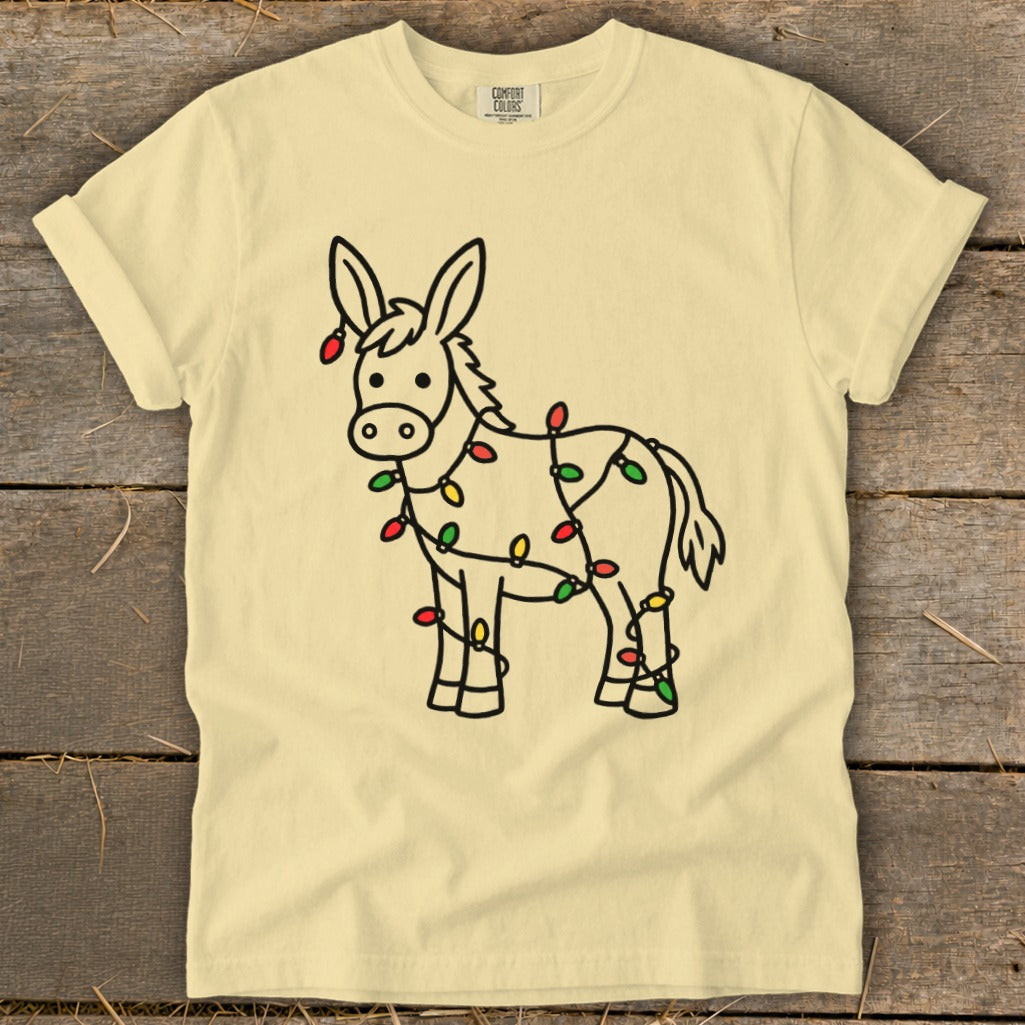 Light yellow t-shirt with line art of a donkey wrapped in colorful Christmas lights.