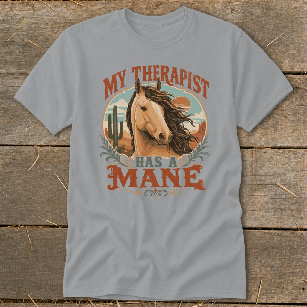 T-shirt with "My therapist has a mane" text and horse illustration in desert landscape.