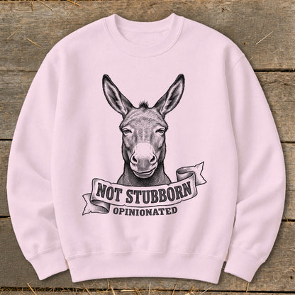 Pink sweatshirt with black line drawing of a donkey head and "NOT STUBBORN OPINIONATED" banner.