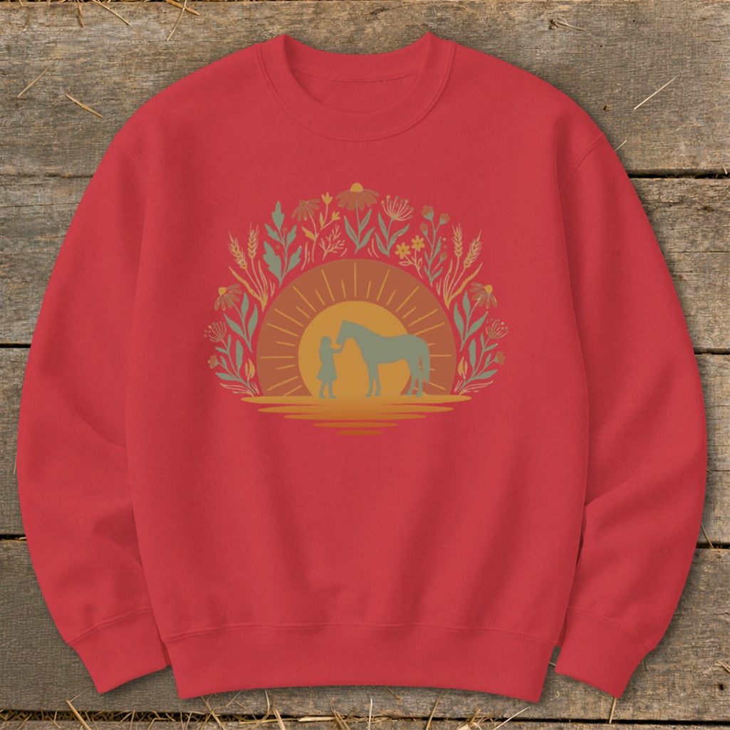 Red sweatshirt with a graphic of a person and horse against a sunset with floral elements.