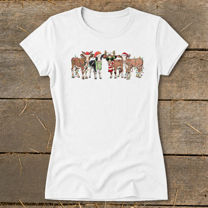 White t-shirt featuring five cartoon cows wearing Christmas hats and lights.