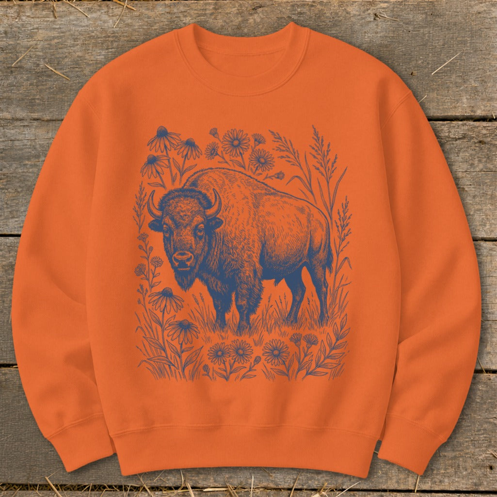 Orange sweatshirt with a blue line art design of a bison surrounded by wildflowers.