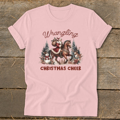 Pink t-shirt with Santa on a horse and "Wrangling Christmas Cheer" text.