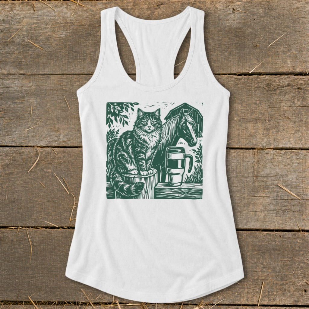 White tank top with green linocut print of cat, horse, barn, and mug.