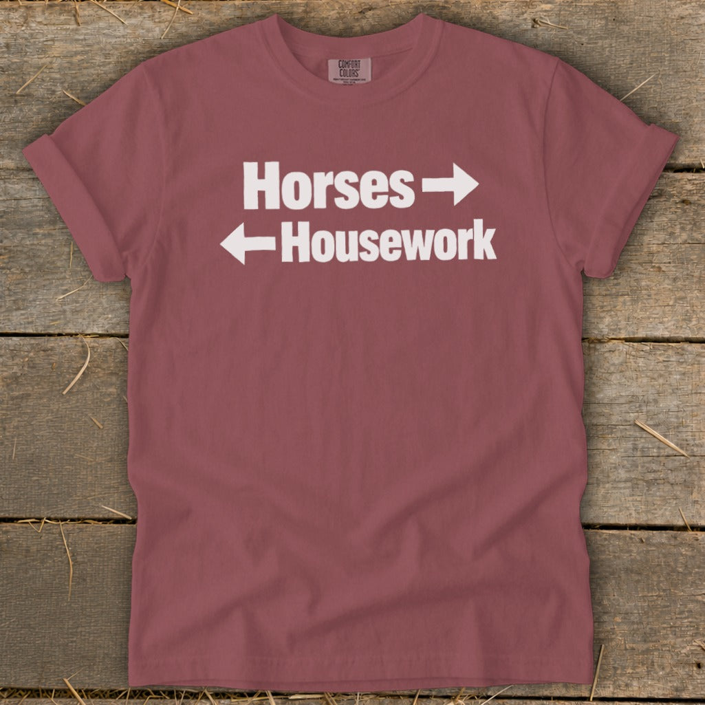 A mauve t-shirt with white text reading "Horses" pointing right and "Housework" pointing left.